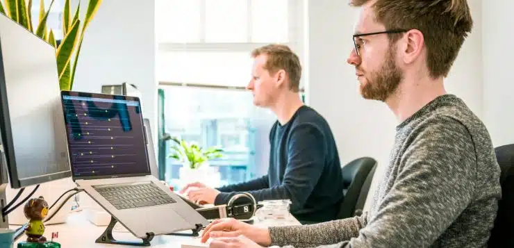 man sitting on chair wearing gray crew-neck long-sleeved shirt using Apple Magic Keyboard