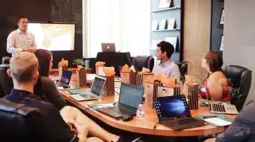 man standing in front of people sitting beside table with laptop computers