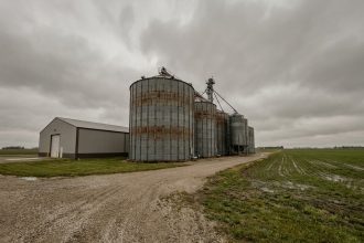 Installations industrielles de stockage agricole avec silos en acier galvanisé et entrepôt moderne dans un paysage rural